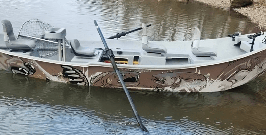 The 18-foot Clackacraft drift boat moored on a river bank, with salmon artwork along the hull