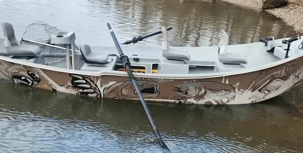 The 18-foot Clackacraft drift boat moored on a river bank, with salmon artwork along the hull