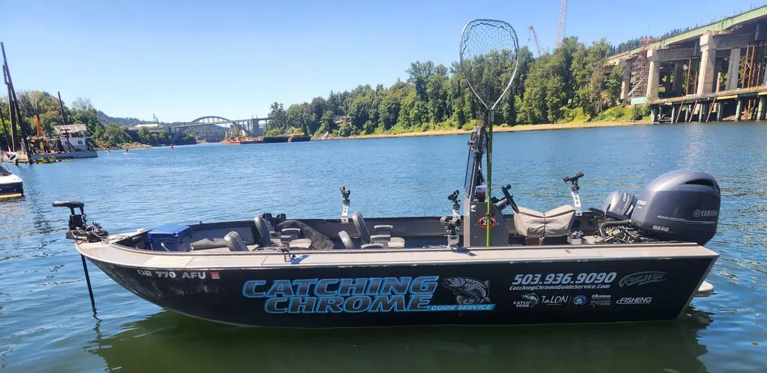 The 22-foot Catching Chrome River Wild sled on the water, rigged with a Yamaha 150 and a landing net