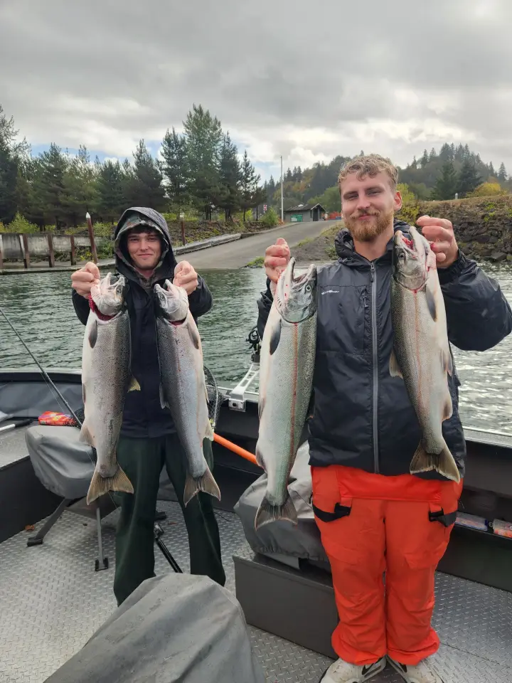Two young men at the boat ramp holding four coho salmon