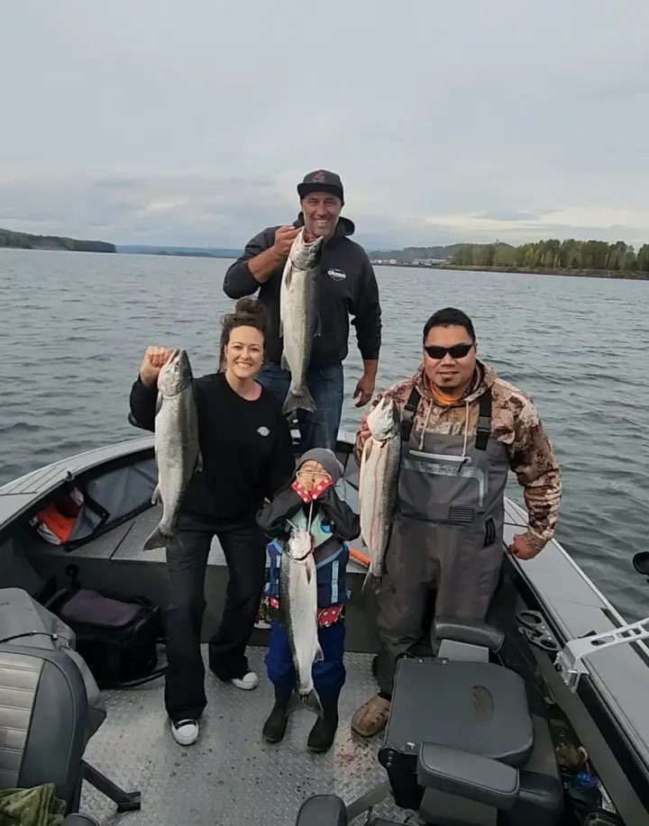 A woman, two men and a small child holding a coho salmon on the boat