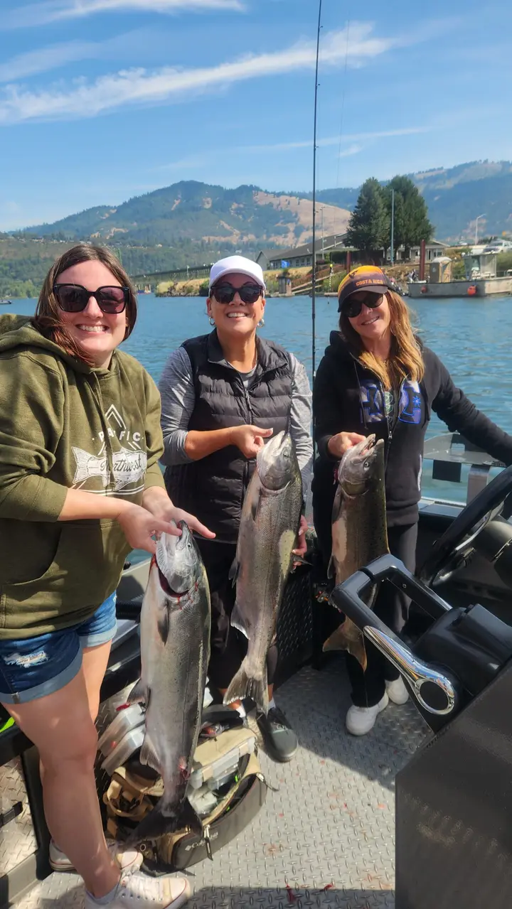 Three women aboard the boat holding three chinook salmon near Hood River