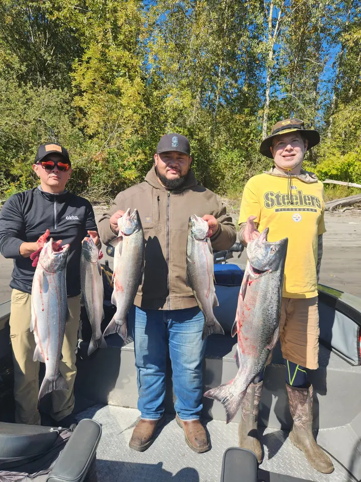Three men aboard the boat holding coho salmon