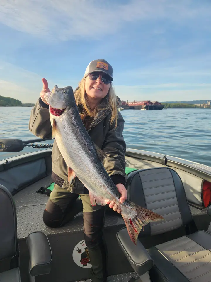 A woman giving a thumbs up while holding a coho salmon