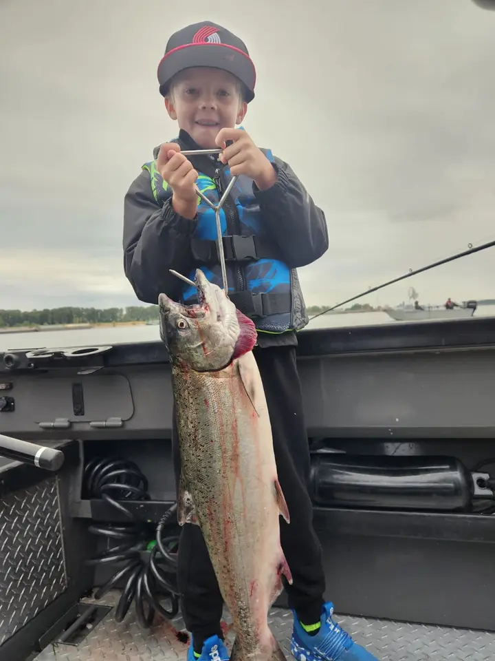 A young boy in a Blazers cap holding a coho salmon