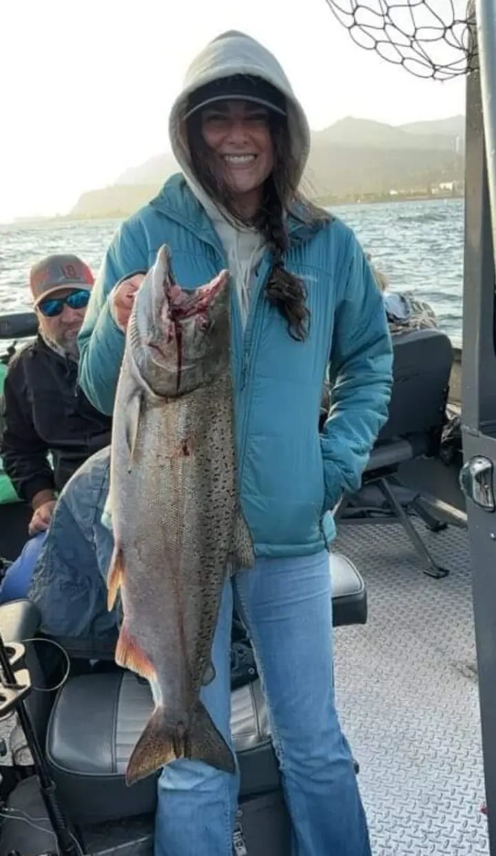 A woman angler holding a coho salmon on the boat