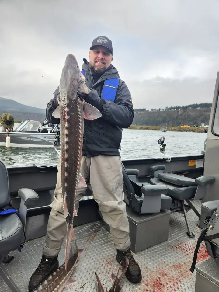 A man holding a big sturgeon on a winter day